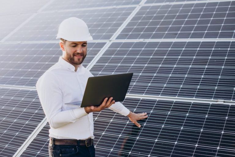 young architect standing by solar panels making diagnostics on computer 800x533 1